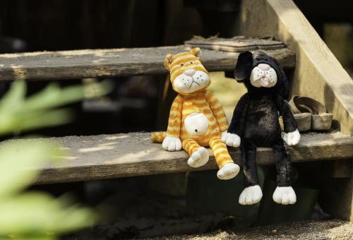 Cuddly toy cat and dog sat on wooden steps